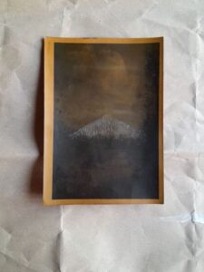 Une montagne émergeant d'un paysage sombre, réalisé en tirage argentique.