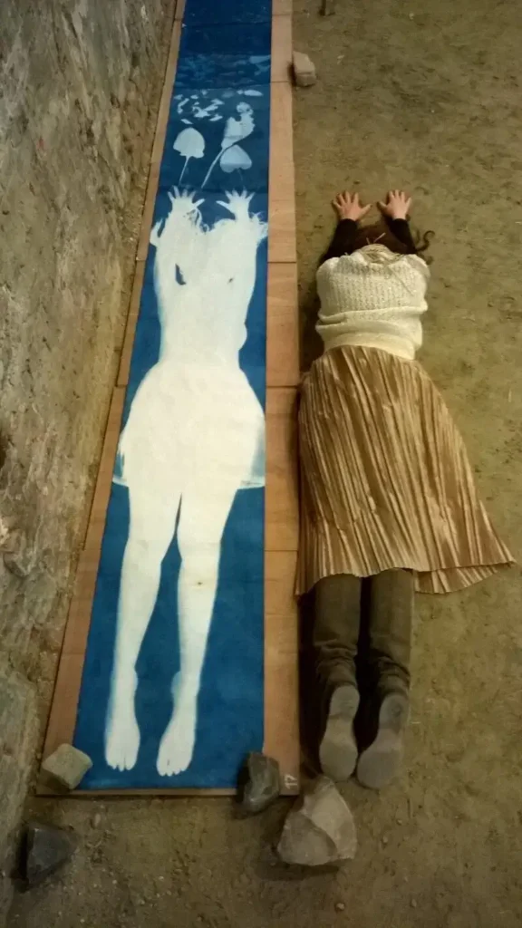 Lysiane Bourdon couchée près de son oeuvre "Blue Me" reproduisant la position du corps cyanotypé